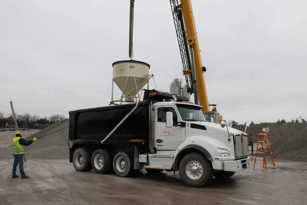 Suspended test bucket dumps aggregate into a haul truck during the WingScan-T NTEP test procedure